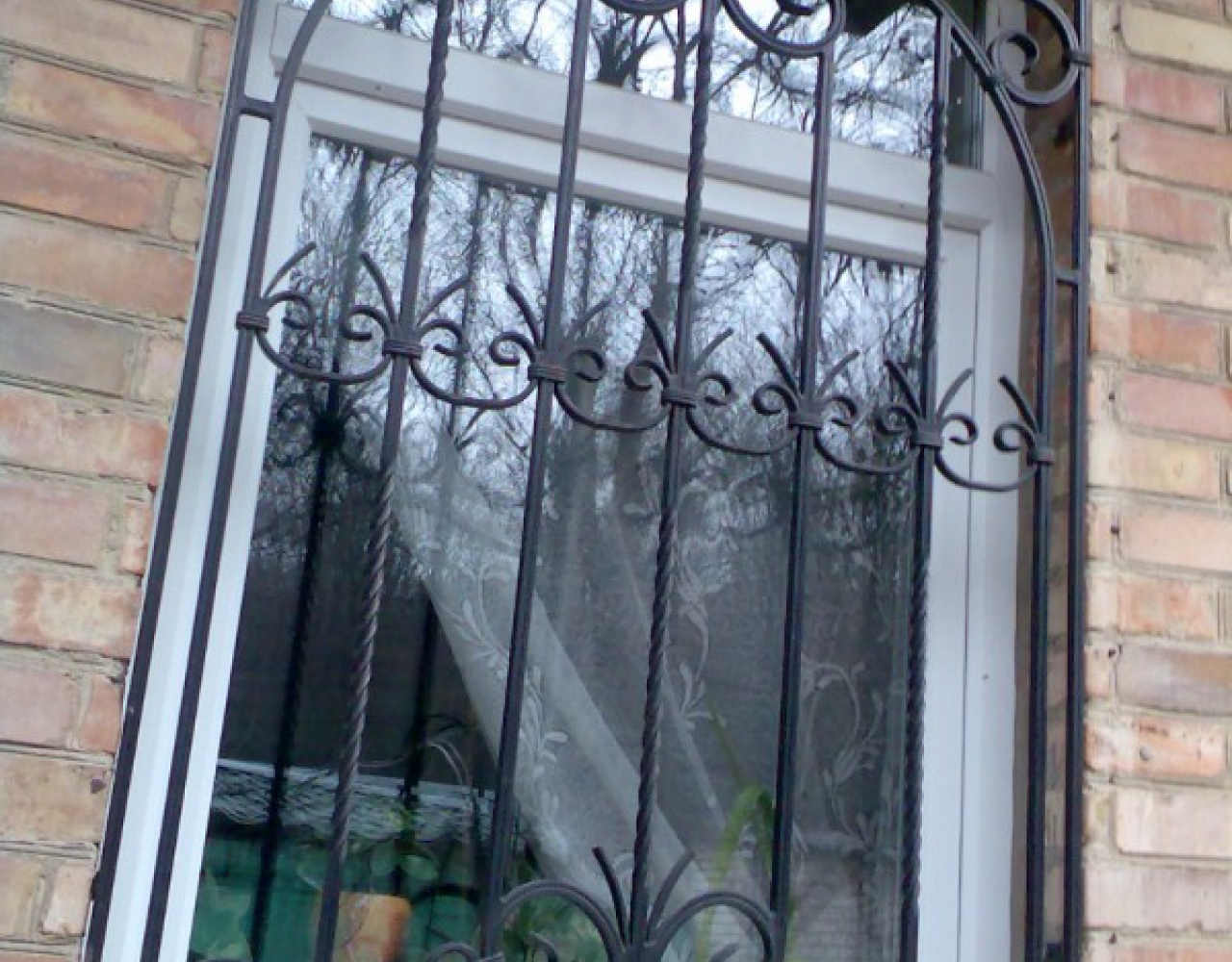 Кованая черная решетка на окно с завитками КР-026